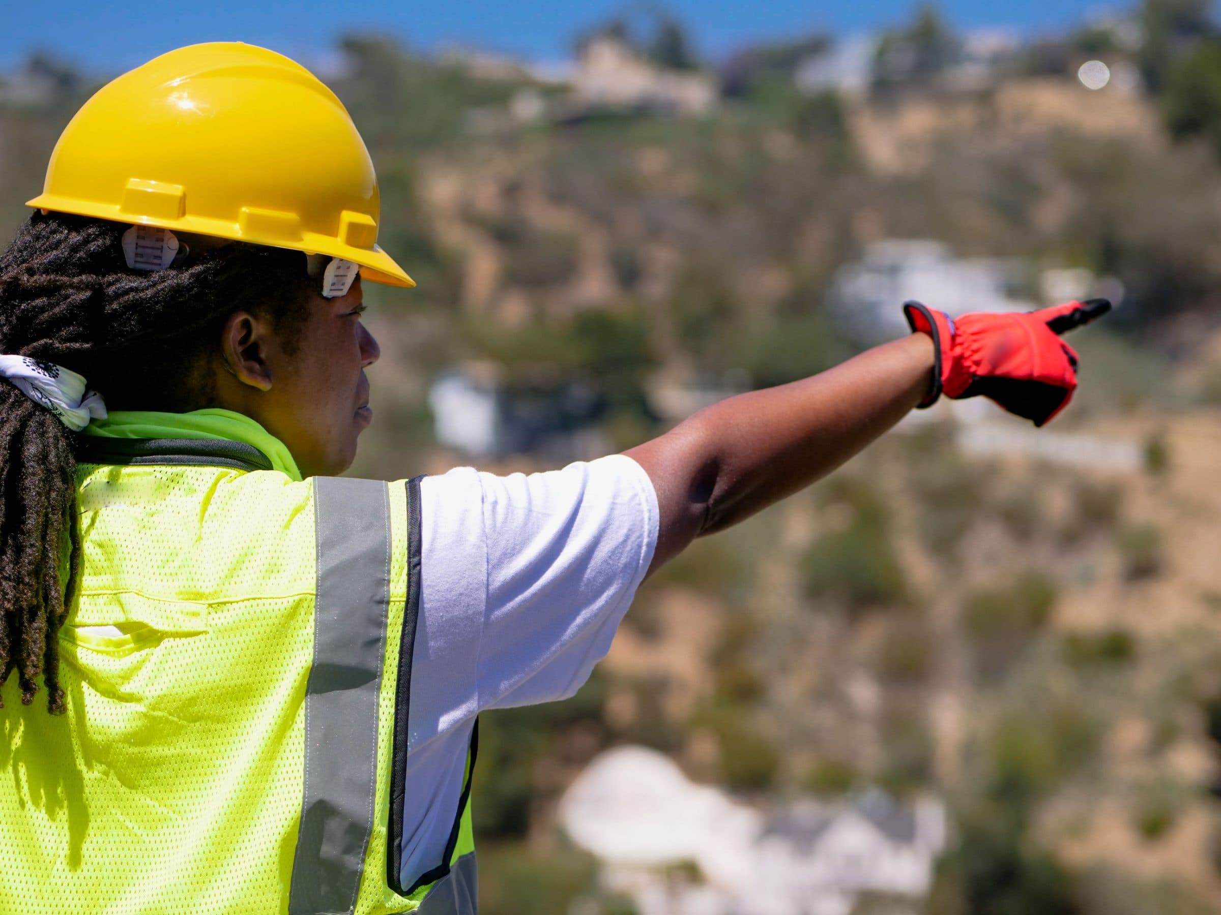 A site supervisor in a hard hat points across an operation